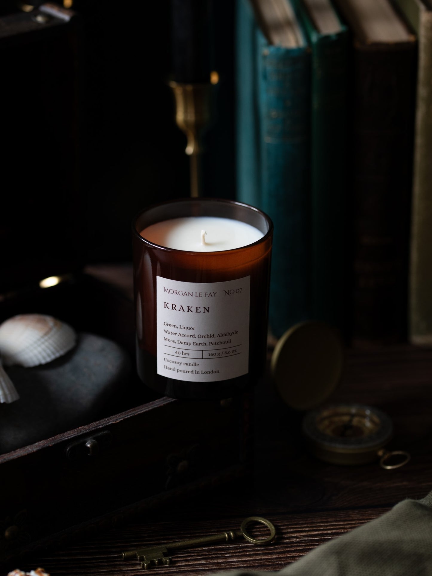 Candle labeled 'Kraken' on a dark background with books and decorative items.