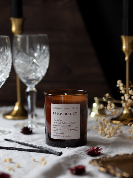 Candle labeled 'Temperance' on a table with glasses and decorative items.