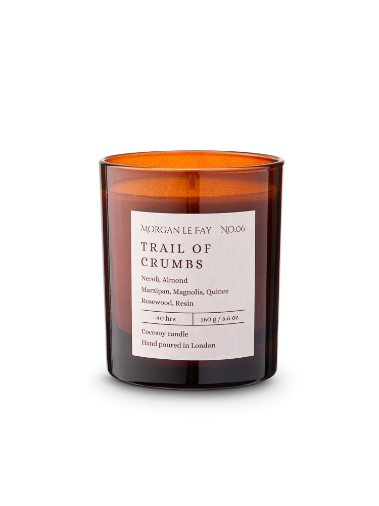 Candle with an amber transparent glass jar and a label that says 'spinning wheel' on a white background