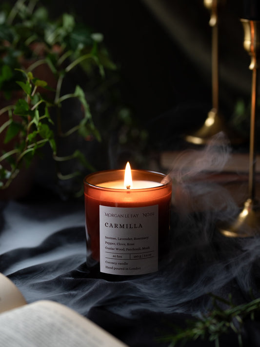 Candle labeled 'Carmilla' with smoke and plants in the background
