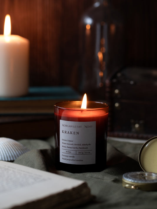 Candle labeled 'Kraken' burning on a table with a dark background