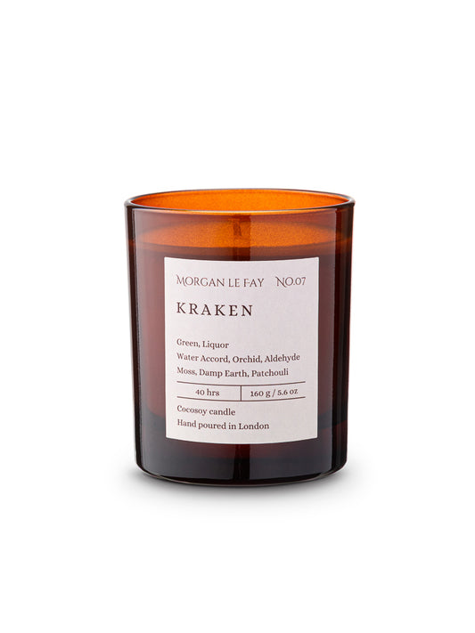 Candle with an amber transparent glass jar and a label that says 'kraken' on a white background