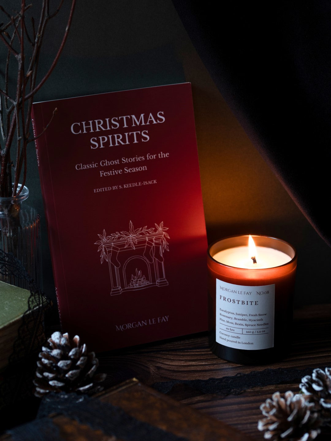 Book titled 'Christmas Spirits' with a lit candle on a dark surface