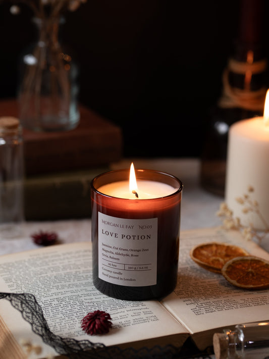 Candle labeled 'Love Potion' on an open book with a dark background