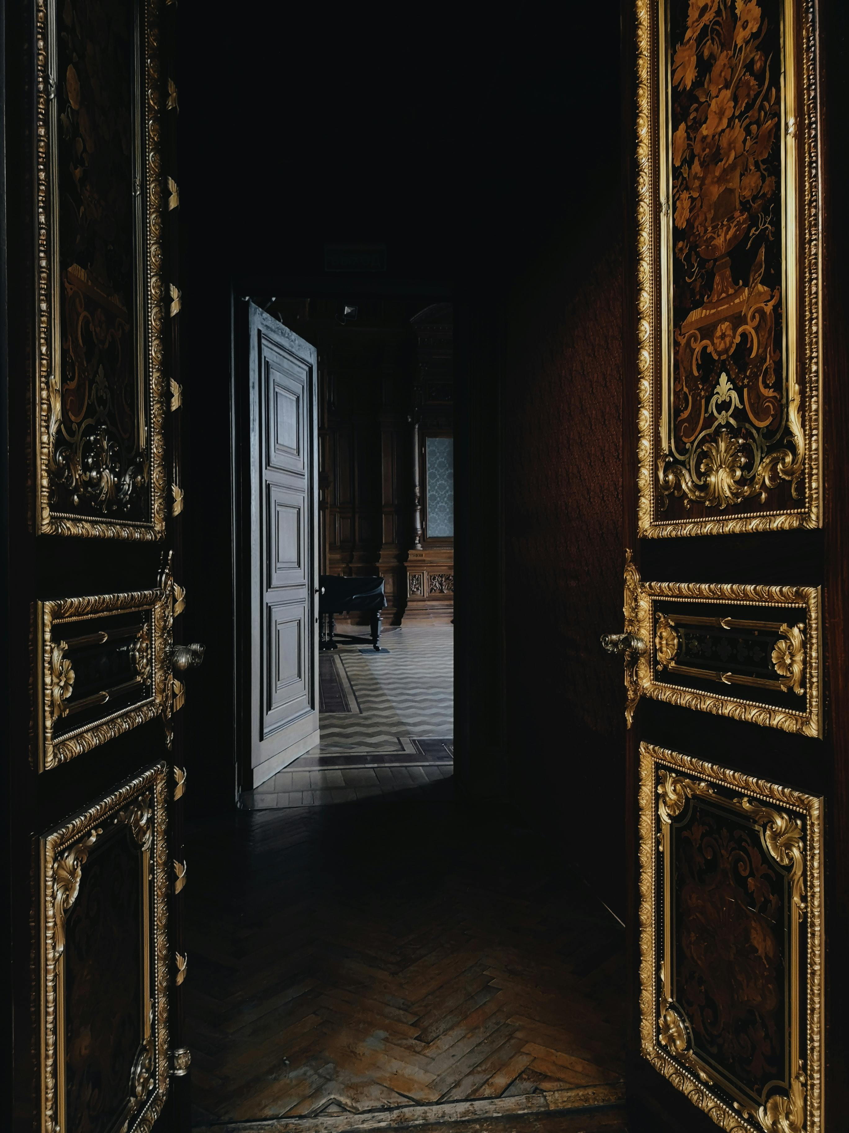 Decorative wooden doors with intricate carvings leading to a dimly lit room.