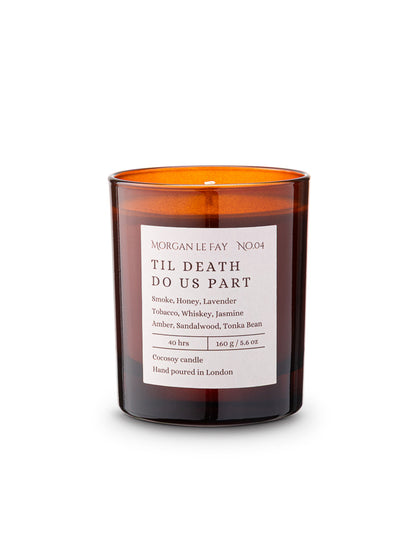 Candle with an amber transparent glass jar and a label that says 'til death do us part' on a white background