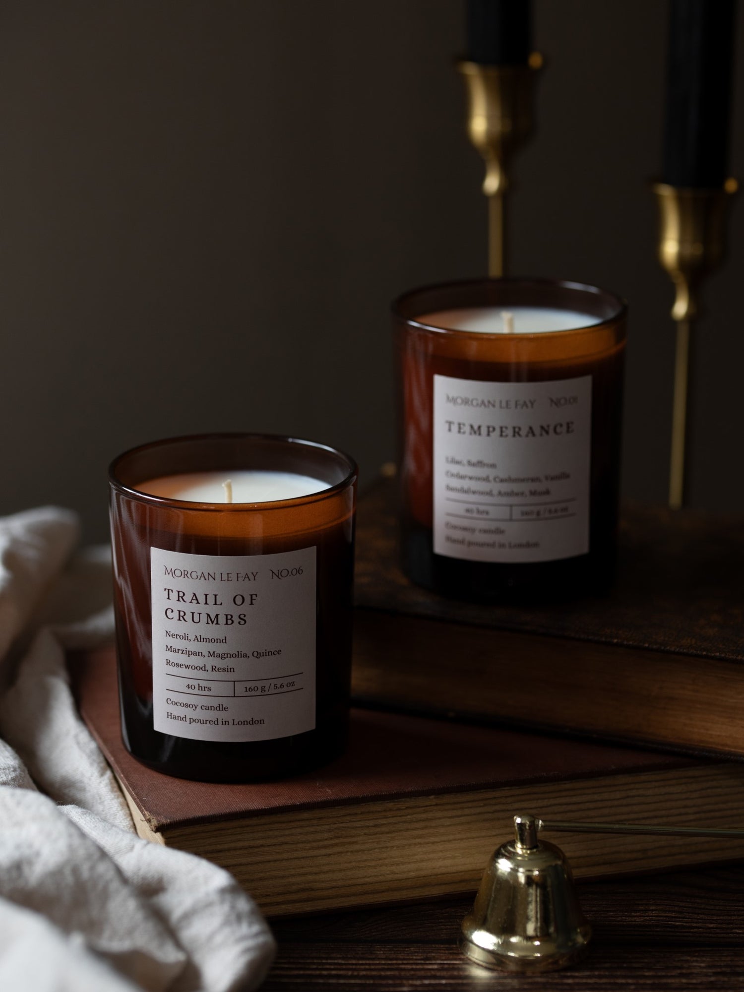 Two candles with labels on a wooden surface with a dark background