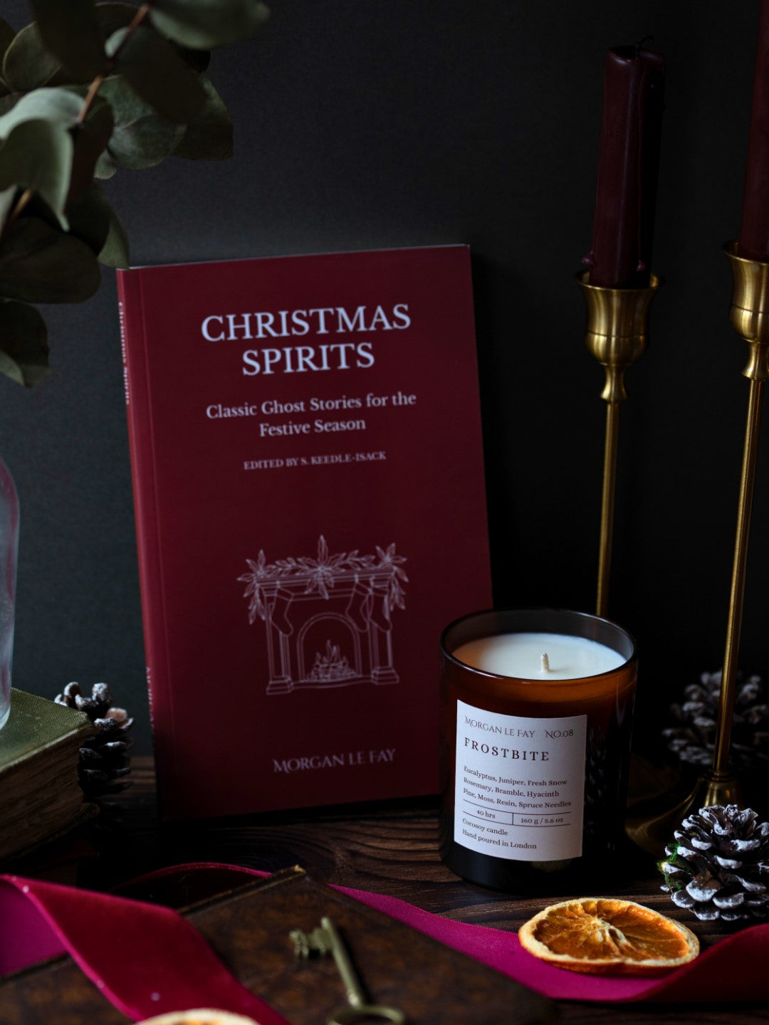 Book titled 'Christmas Spirits' with a candle and decorative elements on a dark surface.
