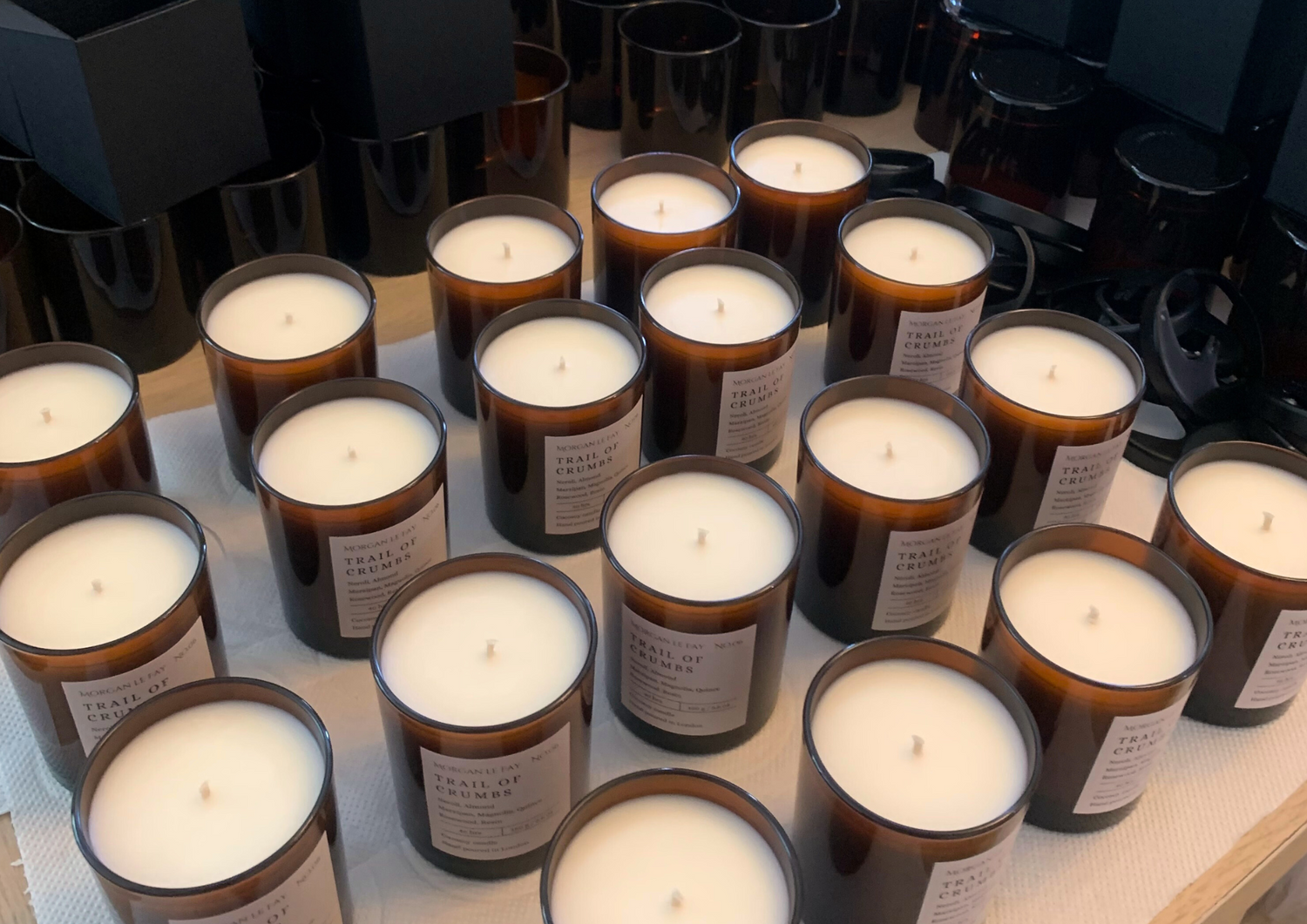 Rows of candles in amber jars with empty boxes and wick holders.